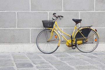 Obraz na płótnie Canvas Old yellow bike on a stone pavement against a plaster wall