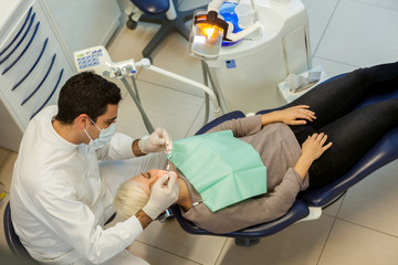 top view of caucasian dentist doing his job on a young blonde wo
