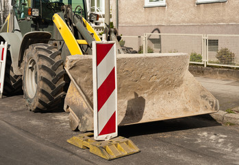 Strassenbau - Ein grosser Radlader parkt am Strassenrand