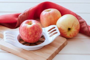 Apples and slicer on a wood background
