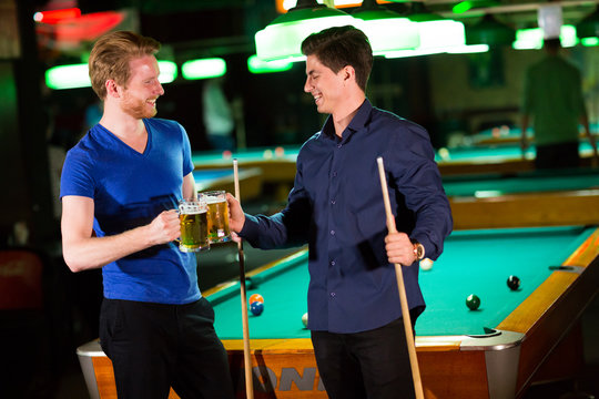 Young men playing pool and drinking beer