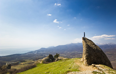 Fototapeta premium man on the cliff in mountains at above sea