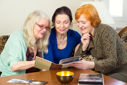 Middle Age Female Friends Looking at Photo Album.