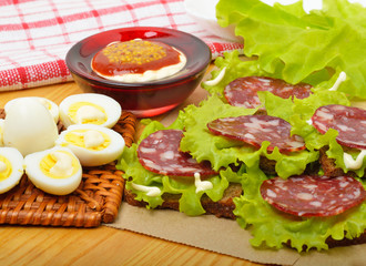 Smoked sausage with quail eggs and lettuc