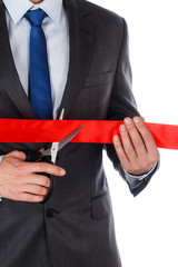 Businessman in suit cutting red ribbon with pair of scissors iso