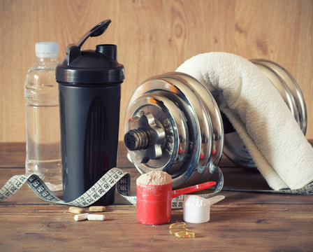 Whey protein powder in scoop with vitamins and plastic shaker