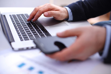 Businessman using laptop and mobile phone