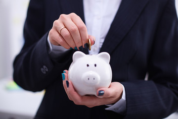 Businesswoman putting  money into a piggy bank isolated on white