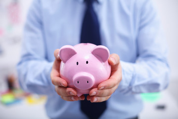 Businessman holding piggy box ,standing in office