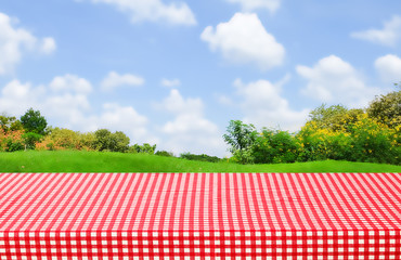 Empty table with red tablecloth over blur park background