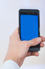 man's hand holding cell phone with empty blue screen