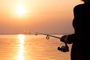 Papier Peint photo autocollant Pêcher jeune fille pêchant au coucher du soleil près de la mer