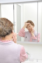 Fototapeta premium 洗面台の鏡の前に立っている一人の高齢者アジア人女性