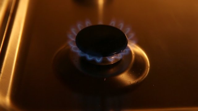 A small gas burner with blue flames in soft light, on and off