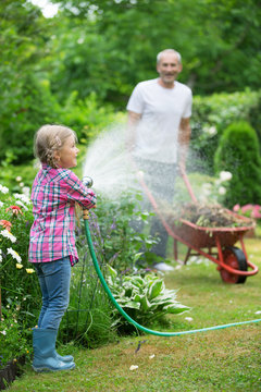 M&auml;dchen spielt mit Gartenschlauch