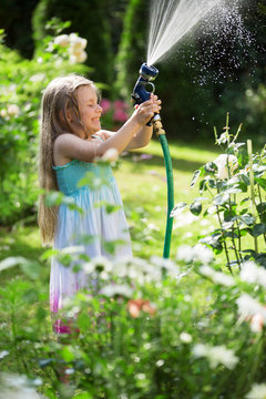 M&auml;dchen spielt mit Gartenschlauch, Spritzwasser