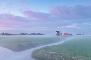 Dutch windmill at misty sunrise