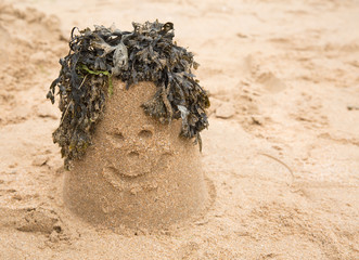 Sandcastle with seaweed making a smiley face