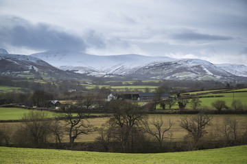 Countryside agricultural landscape with snow covered mountain ra