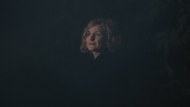 Beautiful young woman standing in a dark park alone at night