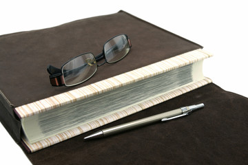 Old text book or bible with pen and eyeglasses and leather bag