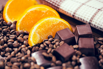 Chocolate, orange and coffee beans on wooden table