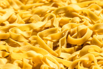 Homemade fresh egg pasta background: italian fettuccine closeup