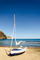 blau weisses Segelboot am Sandstrand