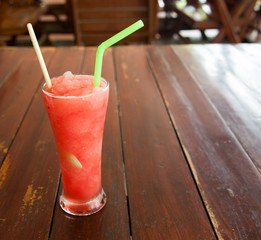 Glass of watermelon smoothie on a wooden table. Selective focus