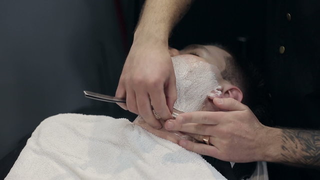 Barber shaves the beard of the client in the barbershoparbershop