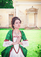 Beautiful young medieval woman in green dress praying