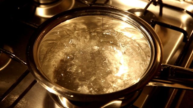 A view of water boiling in a stainless casserole, soft lights