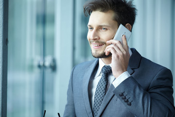 Businessman talking on mobile phone in office lobby