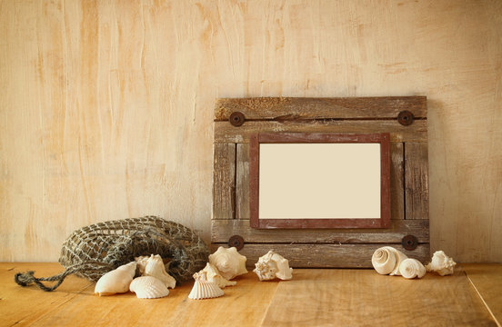 Old nautical wooden frame and natural seashells on wooden table