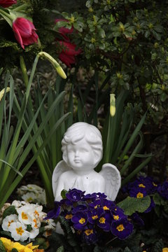 Friedhofsengel zwischen Blumen im Frühling