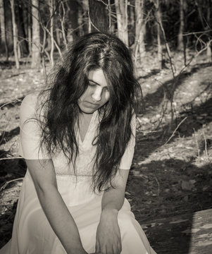 Female teen sitting alone outside in woods -