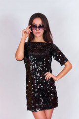 Fototapeta premium Beautiful brunette girl in a black dress and sunglasses.
