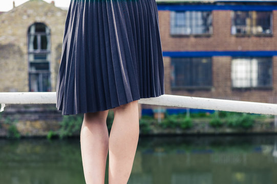 Woman wearing skirt standing on bridge by canal