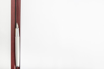 Top view of a pen lying in between two blank sheets of paper