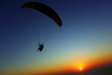 Paraglider silhouette against the background of the sunset sky