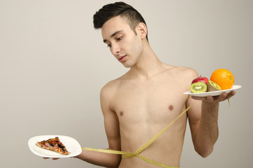 Man choosing between fruits, organic healthy food against pizza