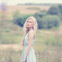 Fototapeta na wymiar portrait of a beautiful blonde in a field in spring