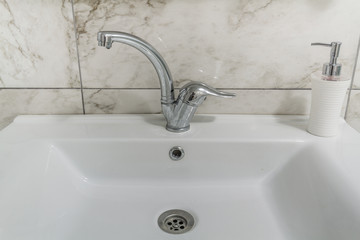 Clean modern bathroom chrome faucet on white cabinet
