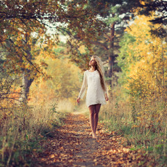Fototapeta premium beautiful young girl on autumn road in autumn dress