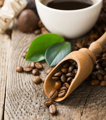 Close-up of coffee cup with roasted coffee beans on wooden background.