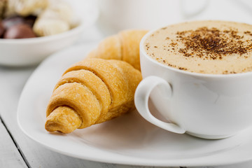 Hot cappuccino and pastries on white wooden boards