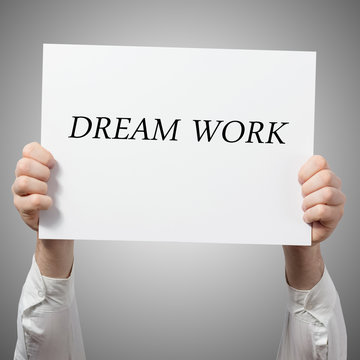 Hands holding placard billboard poster with text: dream work