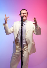 Man in white suit  with microphone. Vivid emotions. Colored back