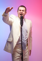 Man in white suit  with microphone. Vivid emotions. Colored back