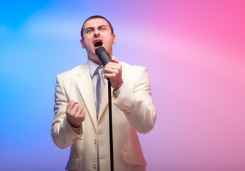 Naklejka premium Man in white suit with microphone. Vivid emotions. Colored back